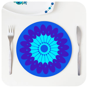 A round retro floral placemat featuring our sunflower design in blues & purples, on a white table with cutlery and vintage serving dish | The Inkabilly Emporium