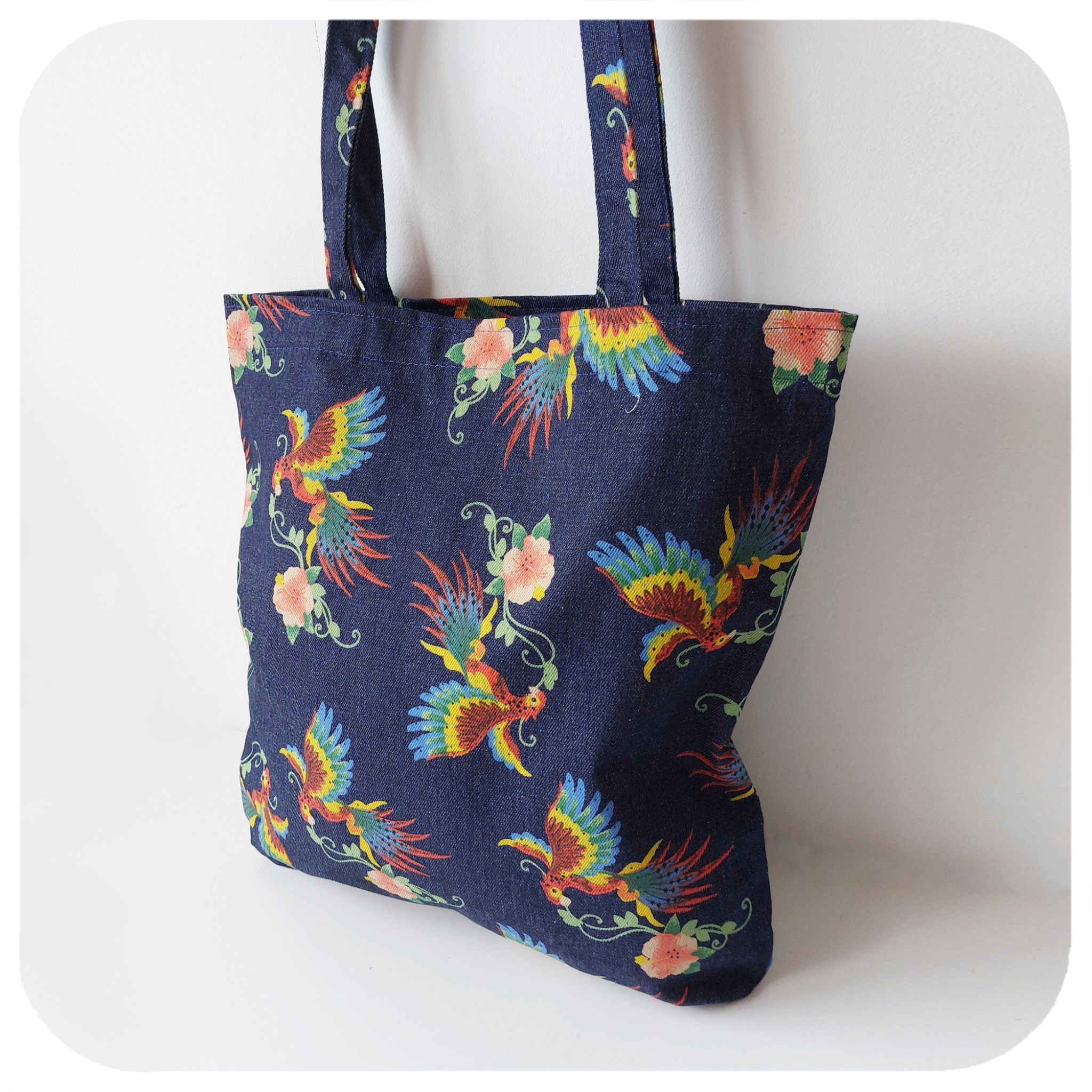 A denim tote bag with printed birds of paradise pattern, on a white background | The Inkabilly Emporium