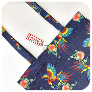 A close up photo of a denim tote bag with printed birds of paradise pattern, on a white background | The Inkabilly Emporium