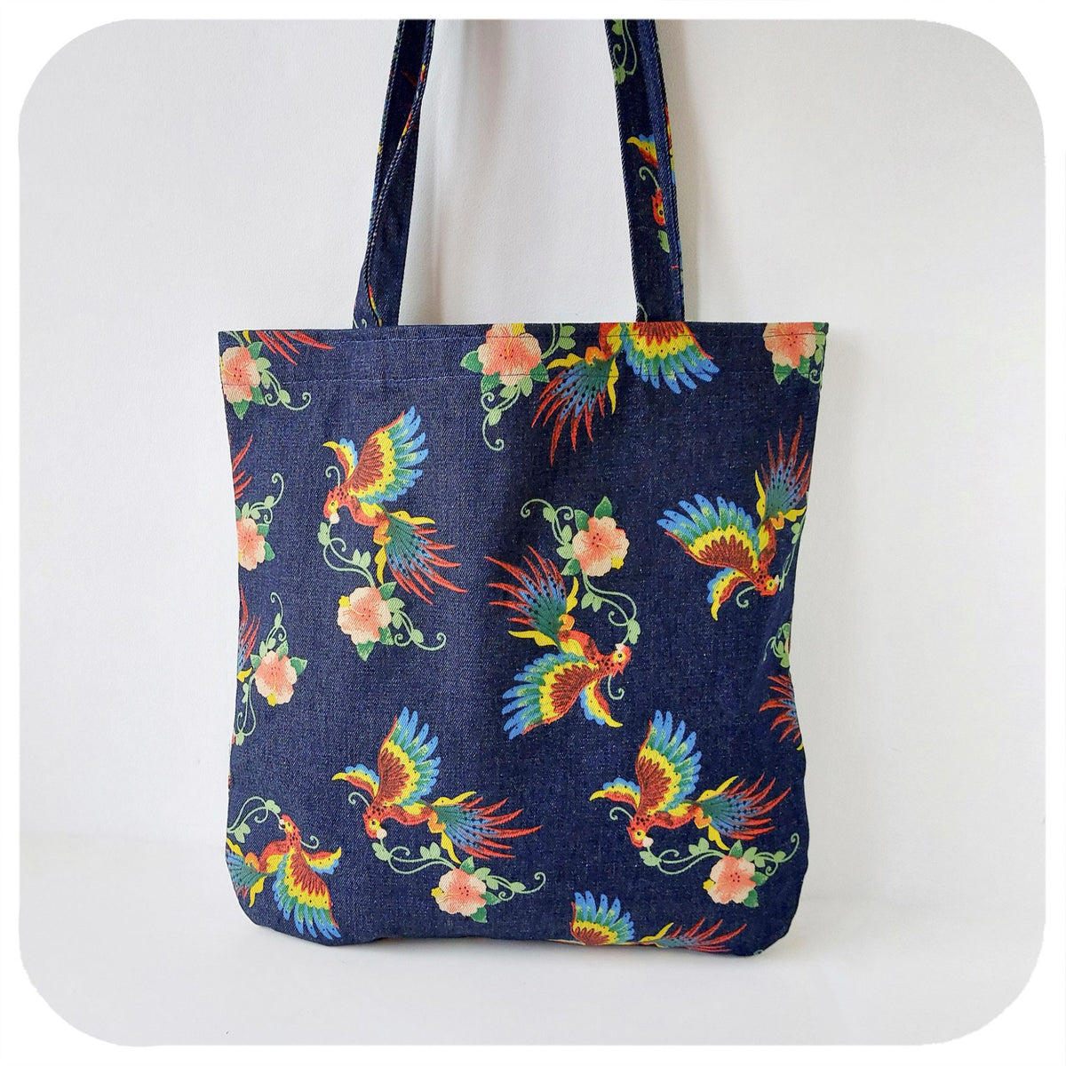 A denim tote bag with printed birds of paradise pattern, on a white background | The Inkabilly Emporium