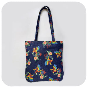 A denim tote bag with printed birds of paradise pattern, on a white background | The Inkabilly Emporium