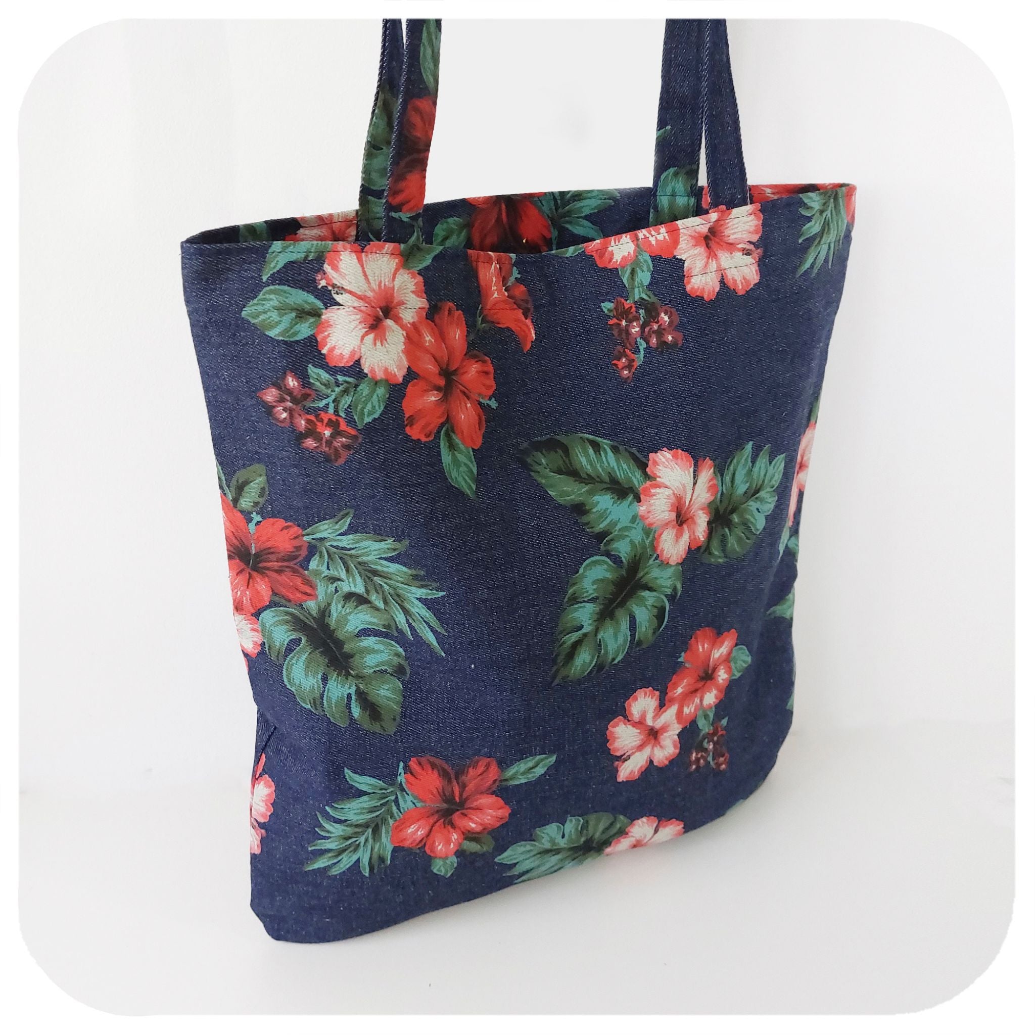 A denim tote bag with printed hibiscus flowers, on a white background | The Inkabilly Emporium