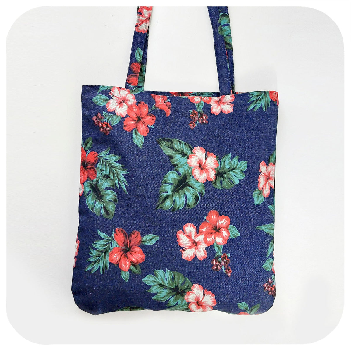 A denim tote bag with printed hibiscus flowers, on a white background | The Inkabilly Emporium