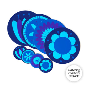 Set of 4 retro floral round placemats in blues & purples, on a white table with matching coasters. Text in bottom right reads: matching coasters available | The Inkabilly Emporium