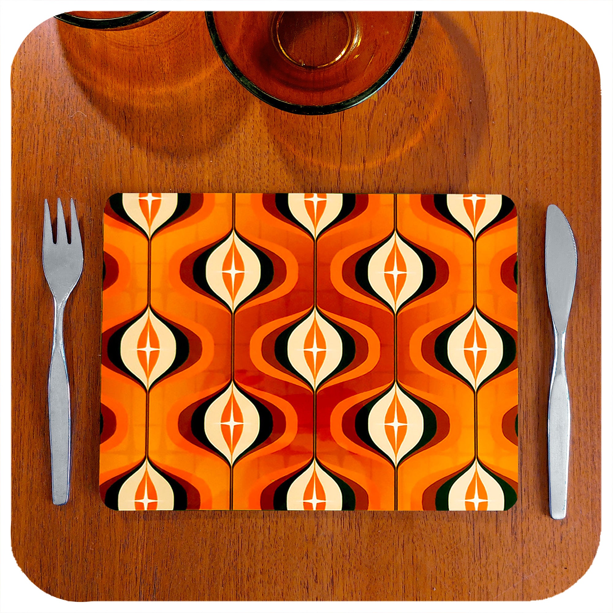 A 70s Op Art style placemat on a teak table with vintage cutlery and glass bowls.