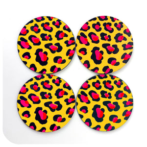 A set of 4 round leopard print coasters in mustard yellow, with orange and hot pink spots on a white background | The Inkabilly Emporium